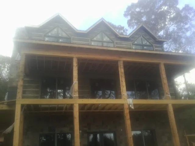 Dormers and porch framing on a large log home under construction — Roof Coating work by our crew in Rich Square