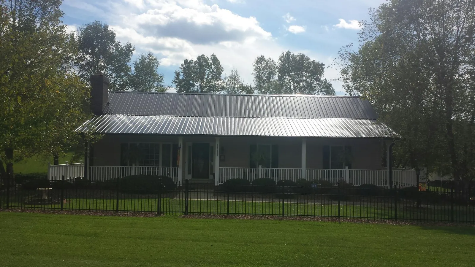Gray metal roof on a brick ranch with a full width front porch — Gutter Guard Installation work by our crew in Rich Square