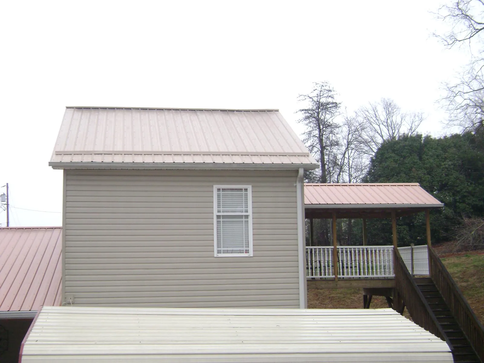 Tan metal roofs on a two story addition and attached porch, from a Roof Replacement job in Rich Square