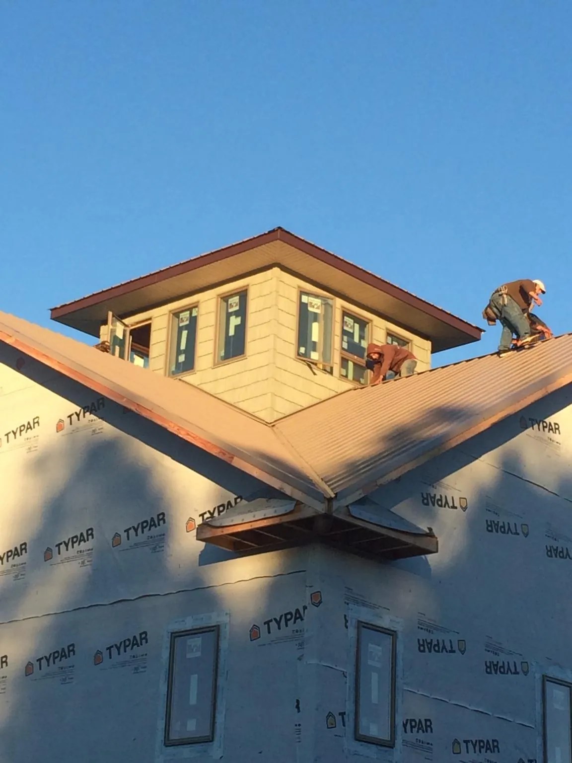 Roofers working around a rooftop cupola on a new metal roof at sunset — Roof Waterproofing in Rich Square by Roofing Brothers